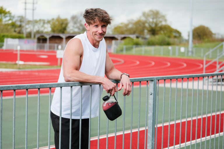 man in white tank top and black shorts holding black dslr camera standing on red metal