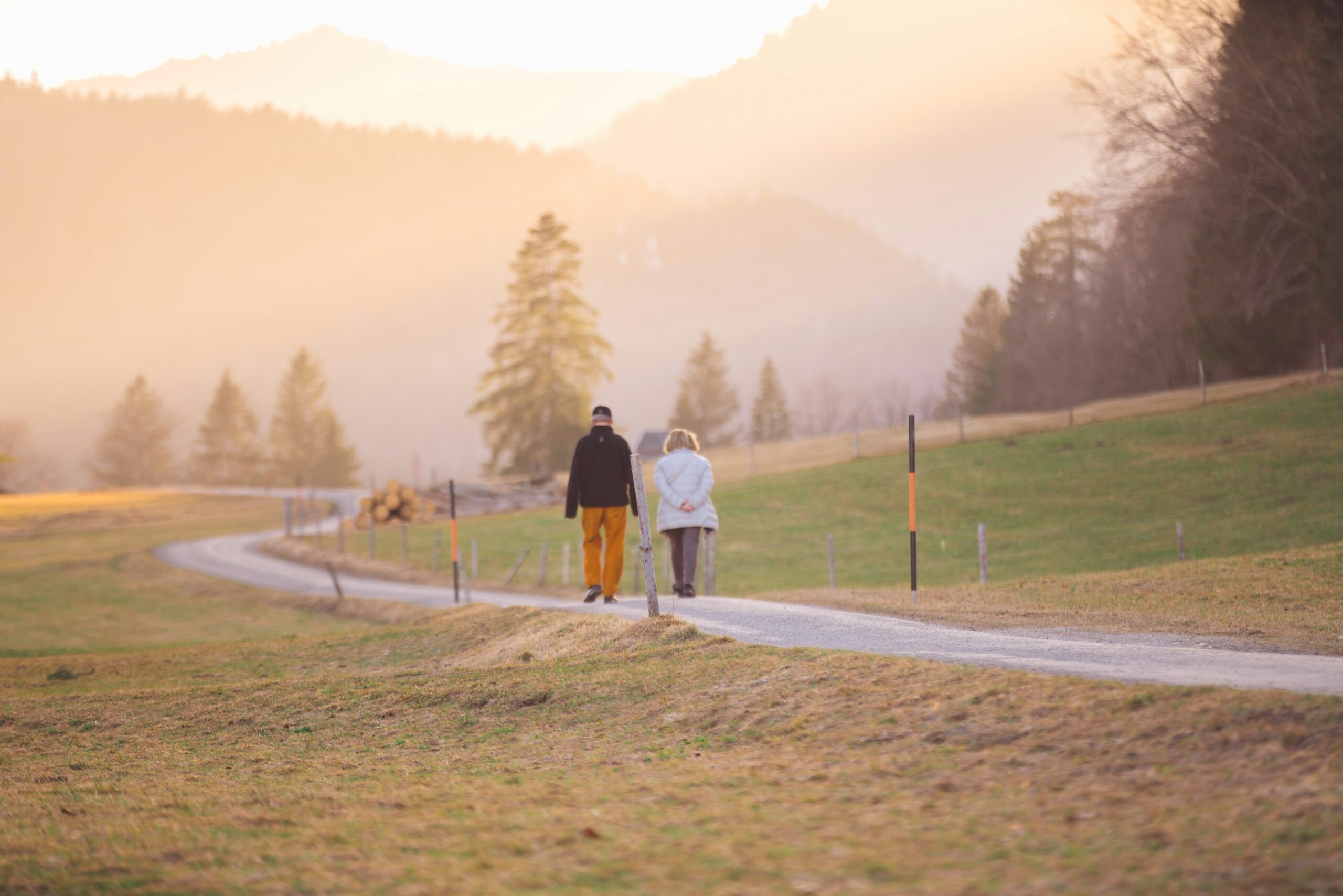 woman in black jacket and white pants walking on road during daytime